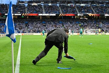 Un empleado de seguridad del club de San Sebastián retira los asientos lanzados desde la zona donde se encontraban los ultras del equipo belga.