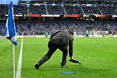 Un empleado de seguridad del club de San Sebastián retira los asientos lanzados desde la zona donde se encontraban los ultras del equipo belga.