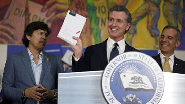 El gobernador de California, Gavin Newsom, en el centro, sostiene el proyecto de ley de alivio del Plan de Retorno de California después de firmarlo junto al concejal de la ciudad de Los Ángeles Kevin de Leon, a la izquierda, y el alcalde de Los Ángeles, Eric Garcetti, el martes 13 de julio de 2021 en Los Ángeles.