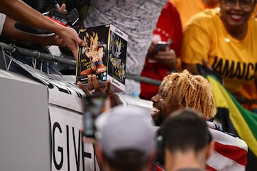El medallista de oro Noah Lyles, del equipo estadounidense, recibe una figura de Dragon Ball de manos de un fan tras competir en la final masculina de 200 metros lisos, en el séptimo día del Campeonato Mundial de Atletismo Tokio. 