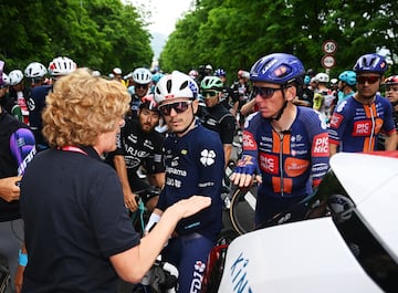 Los ciclistas franceses David Gaudu y Romain Bardet hablan con una mujer de la organizaci¨®n tras la neutralizaci¨®n de la carrera.