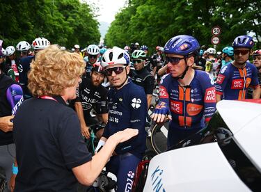 Los ciclistas franceses David Gaudu y Romain Bardet hablan con una mujer de la organización tras la neutralización de la carrera. 