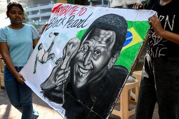 Los estudiantes se paran cerca de una pintura de la leyenda del fútbol brasileño Pelé como parte del homenaje, en una escuela de arte en Mumbai.