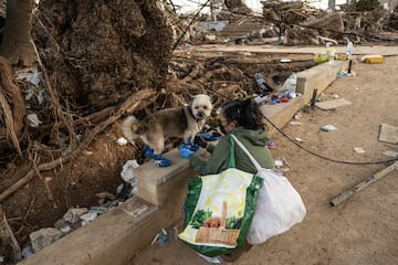 Una mujer protege las patas de su perro con plásticos mientras la zona se recupera de las inundaciones generalizadas de la semana pasada el 9 de noviembre de 2024 en el municipio de Paiporta, cerca de Valencia, España.