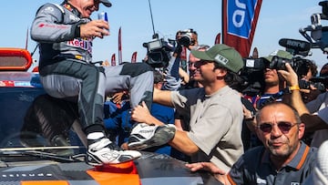 Team Audi Sport's Spanish driver Carlos Sainz (L) is congratulated by his son Formula 1 driver Carlos Sainz Jr. after crossing the finish line of stage 12 from Yanbu to Yanbu, Saudi Arabia, on January 19, 2024, at the end of the Dakar rally 2024. Veteran Spanish driver Carlos Sainz won on January 19, 2024 the gruelling Dakar Rally for a fourth time on Friday, becoming at 61 the oldest winner of the race. (Photo by PATRICK HERTZOG / AFP)