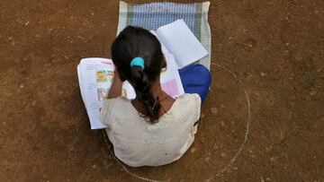 A girl, who has missed her online classes due to a lack of internet facilities, sits on the ground in a circle drawn with chalk to maintain safe distance as she listens to pre-recorded lessons over loudspeakers, after schools were closed following the cor