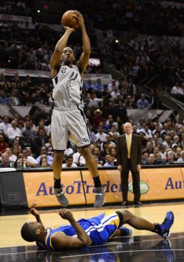 Spurs 129 - Warriors 127 (1-0). El jugador Harrison Barnes de los Warriors en el suelo y Kawhi Leonard de los Spurs tira a canasta.