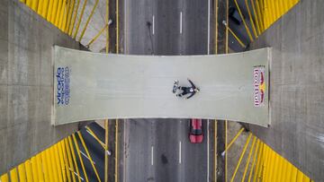 Plano cenital de la miniramp sobre el Ponte Estaiadinha de Sao Paulo (Brasil), con Sandro Dias y su tabla de skate estirados en el centro y un coche rojo pasando por debajo.