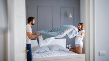 Charming beautiful couple in love making the bed together and having fun.
