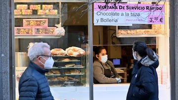 MADRID, 05/12/2020.- Dos personas pasan ante la conocida pastelería La Mayorquina en la puerta del Sol de Madrid, este sábado. El centro de Madrid no verá este año las clásicas aglomeraciones de turistas durante el puente de la Constitución para disfrutar del alumbrado, las compras, los puestos de castañas, los mercadillos navideños o para adquirir décimos de Lotería, tradiciones que solo podrán cumplir los vecinos de la región y bajo restricciones y limitaciones de aforos. EFE/Victor Lerena