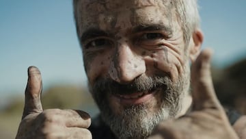Un hombre levanta los pulgares, con la cara llena de barro, sonriendo, durante una edición de la Bestial Race.