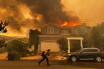 Una residencia arde mientras un bombero combate el incendio de Palisades en el vecindario de Pacific Palisades en Los ?ngeles.