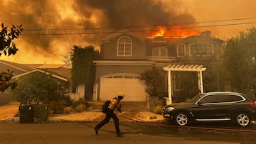 Una residencia arde mientras un bombero combate el incendio de Palisades en el vecindario de Pacific Palisades en Los Ángeles.