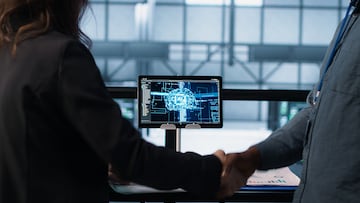 Manager meeting with client in data center to review files, doing handshake after finalizing deal. Server room supervisor reaching agreement with customer after checking documentation, camera A