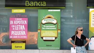 Imagen de una mujer junto a una sucursal de Bankia.