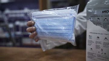 Una farmacéutica enseña a un cliente un paquete de mascarillas