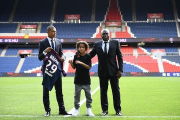 Paris Saint-Germain's new forward Kylian Mbappe (L) together with father Wilfried Mbappe and his brother Ethan holds his jersey during his presentation at the Parc des Princes stadium in Paris on September 6, 2017.