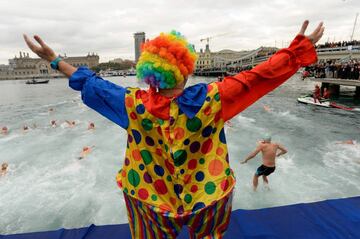 A participant in a clown suit gestures before jumping into the water during the 108th edition of the 'Copa Nadal' (Christmas Cup) swimming competition in Barcelona's Port Vell on December 25, 2017.  
The traditional 200-meter Christmas swimming race gathered more than 300 participants on Barcelona's old harbour.   / AFP PHOTO / Josep LAGO