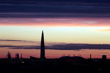 La torre de negocios Lakhta Center en construcción y el estadio de San Petersburgo al atardecer.