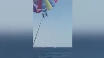 Dos personas practican paravelismo en Jordania, a unos cuantos metros sobre el agua del mar, con un paracaídas de colores.