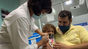 Pedro Montano sostiene a su hija Roxana Montano, de 3 años, mientras es inoculada contra el COVID-19 con la vacuna cubana Soberana Plus, en el hospital Juan Manuel Márquez de La Habana, como parte de un estudio de vacunas en niños y adolescentes.