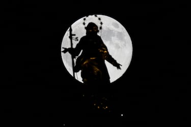 La superluna de la Luna del Castor se oculta tras la estatua de la Madonnina en lo alto de la Catedral del Duomo, en Milán.