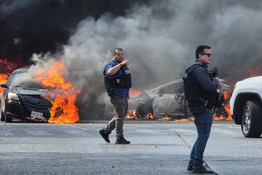 Policías resguardan la zona donde el crimen organizado quemó vehículos para bloquear una carretera tras el operativo en el que habría muerto “El Mencho”.