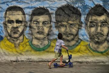 Un niño mira un graffiti que muestra a jugadores de fútbol brasileños que participan en la próxima Copa Mundial 2018.