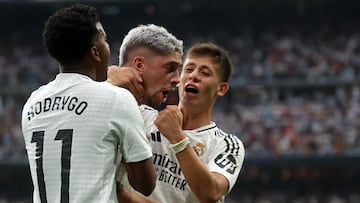 Real Madrid's Uruguayan midfielder #08 Federico Valverde (C) celebrates scoring the opening goal with Real Madrid's Brazilian forward #11 Rodrygo and Real Madrid's Turkish midfielder #15 Arda Guler during the Spanish league football match between Real Madrid CF and Real Valladolid FC at the Santiago Bernabeu stadium in Madrid on August 25, 2024. (Photo by Pierre-Philippe MARCOU / AFP)