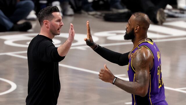 Head coach JJ Redick of the Los Angeles Lakers high fives LeBron James #23 during the third quarter against the Dallas Mavericks at American Airlines Center on April 09, 2025 in Dallas, Texas.