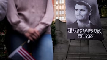 Una persona sostiene una bandera estadounidense mientras la gente se reúne durante una vigilia en memoria del activista y comentarista de derecha estadounidense Charlie Kirk.