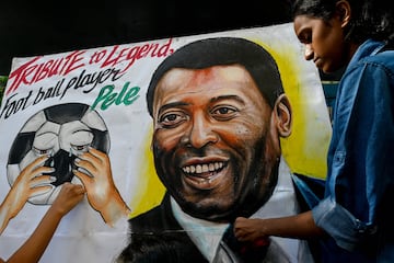 Los estudiantes se paran cerca de una pintura de la leyenda del fútbol brasileño Pelé como parte del homenaje, en una escuela de arte en Mumbai.