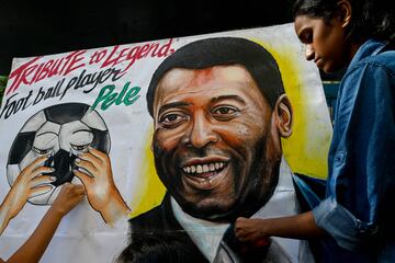 Los estudiantes se paran cerca de una pintura de la leyenda del fútbol brasileño Pelé como parte del homenaje, en una escuela de arte en Mumbai.