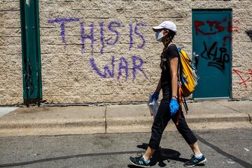 A woman walks by a graffiti spelling "This Is War" following a day of demonstration in a call for justice for George Floyd, who died while in custody of the Minneapolis police, on May 30, 2020 in Minneapolis, Minnesota. - Demonstrations are being held across the US after George Floyd died in police custody on May 25. (Photo by Kerem Yucel / AFP)