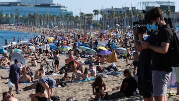 Journalists record as people enjoy the sunny weather at the Barceloneta beach, after Catalonia's regional authorities and the city council announced restrictions to contain the spread of the coronavirus disease (COVID-19) in Barcelona, Spain July 19, 2020. REUTERS/Nacho Doce