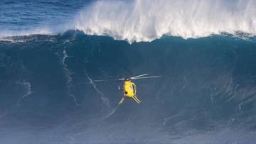 Un helic&oacute;ptero amarillo de la World Surf League (WSL) frente a la peligrosa ola gigante de Jaws (Pe&#039;ahi, Maui, Haw&aacute;i, Estados Unidos) durante el evento de surf de olas gigantes Pe&#039;ahi Challenge 2017.