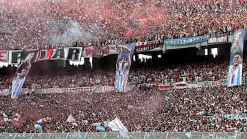 Banners depicting Argentina's German Pezzella (L), Lionel Messi (C) and Enzo Fernandez lifting the trophy after winning the Qatar 2022 World Cup are displayed on the stands as supporters of River Plate cheer for their team during the Argentine Professional Football League tournament match against Argentinos Juniors at El Monumental stadium in Buenos Aires, on February 12, 2023. (Photo by ALEJANDRO PAGNI / AFP)