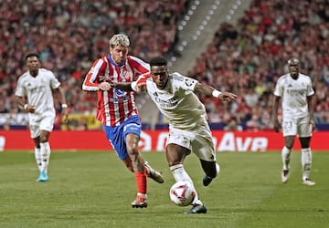 Vinicius avanza con la pelota controlada con la oposición de Rodrigo de Paul.