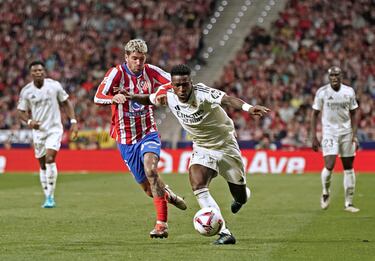 Vinicius avanza con la pelota controlada con la oposición de Rodrigo de Paul.