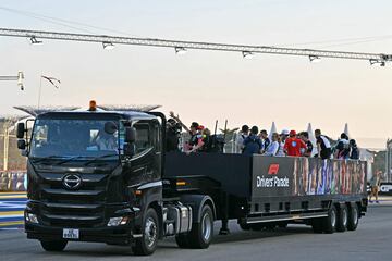 Los pilotos de Fórmula Uno se suben a la parte trasera de un camión para el desfile de pilotos antes de la carrera.