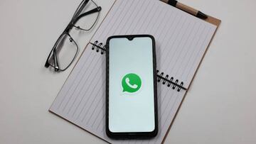 In this photo illustration a WhatsApp logo is displayed on a smartphone screen above a notebook next to glasses in Athens, Greece on April 4, 2023. (Photo illustration by Nikolas Kokovlis/NurPhoto via Getty Images)