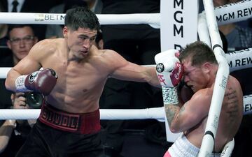 Dmitry Bivol (L) throws a left at Canelo Alvarez in the fifth round of their WBA light heavyweight title