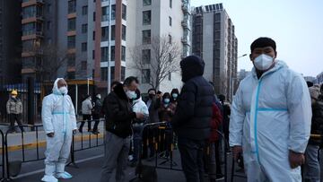 Workers in protective suits stand guard as residents line up to take nucleic acid testing during a mass testing for the coronavirus disease (COVID-19), at a makeshift testing site near a residential compound in Beijing. China March 20, 2022. REUTERS/Tings