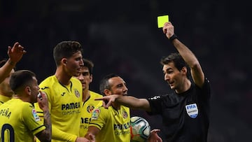 Spanish referee Ricardo de Burgos shows a yellow card to Villarreal's Spanish midfielder Ruben Pena during the Spanish league football match Club Atletico de Madrid against Villarreal CF at the Wanda Metropolitano stadium in Madrid on February 23,