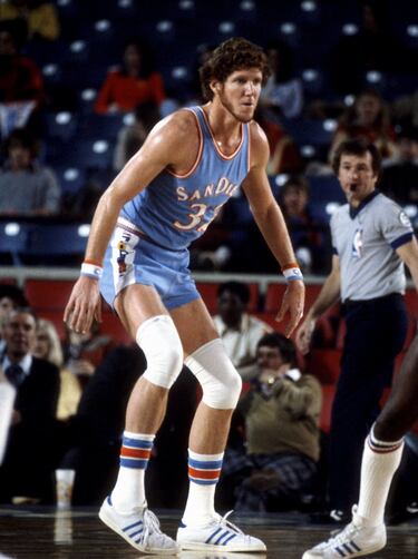 Equipos NBA: Portland Trail Blazers (1974-1979), San Diego/Los Angeles Clippers (1979-1985), Boston Celtics (1985-1988). Dos veces campeón (una en los setenta), una vez MVP, una vez MVP de las Finales, dos veces all star. Promedio en su carrera NBA: 13,3 puntos, 10,5 rebotes y 2,2 tapones. Mejor temporada NBA en los setenta, 1976-77: 18,6 puntos, 14,4 rebotes, 3,2 tapones.

Las lesiones (ese maldito pie...) impidieron que se convirtiera en uno de los mejores pívots en la historia. Después de un tramo extraordinario en UCLA, desató la blazermania en Portland: campeón, MVP de las Finales y la Regular Season... luego llegaron las lesiones y otro anillo, ya en 1986 y como sexto hombre de los Celtics. Extraordinario defensor, perfecto líder y uno de los mejores pívots pasadores de la historia. El gigante rojo.