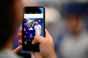 A football fan takes a picture of a friend posing with the UEFA Champions League trophy after it was unveiled in Madrid on May 29, 2019 ahead of the final football match between Liverpool and Tottenham Hotspur on June 1.