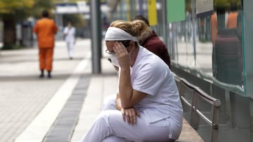 Una trabajadora sanitaria protegida se sienta en uno de los bancos de las inmediaciones del hospital de campaña montado en IFEMA.