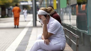 Una trabajadora sanitaria protegida se sienta en uno de los bancos de las inmediaciones del hospital de campa&ntilde;a montado en IFEMA.