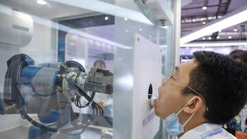 BEIJING, CHINA - AUGUST 18: A staff member takes part in a demonstration of a robot arm collecting swab samples for coronavirus disease (COVID-19) detection during the 2022 World Robot Conference at Beijing Etrong International Exhibition on August 18, 2022 in Beijing, China. The 2022 World Robot Conference kicked off on Thursday in Beijing. (Photo by Lintao Zhang/Getty Images)