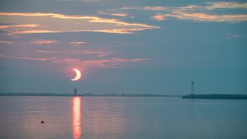 En esta foto, tomada el 10 de junio de 2021, se ve un eclipse solar parcial mientras el Sol sale detrás del Faro del Rompeolas de Delaware, en Lewes Beach, Delaware.